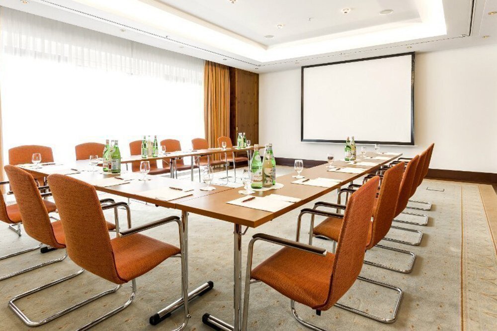Blick in den Tagungsraum "Pine Room" in Hamburg mit großer Leinwand und U-förmig aufgereiten Tischen