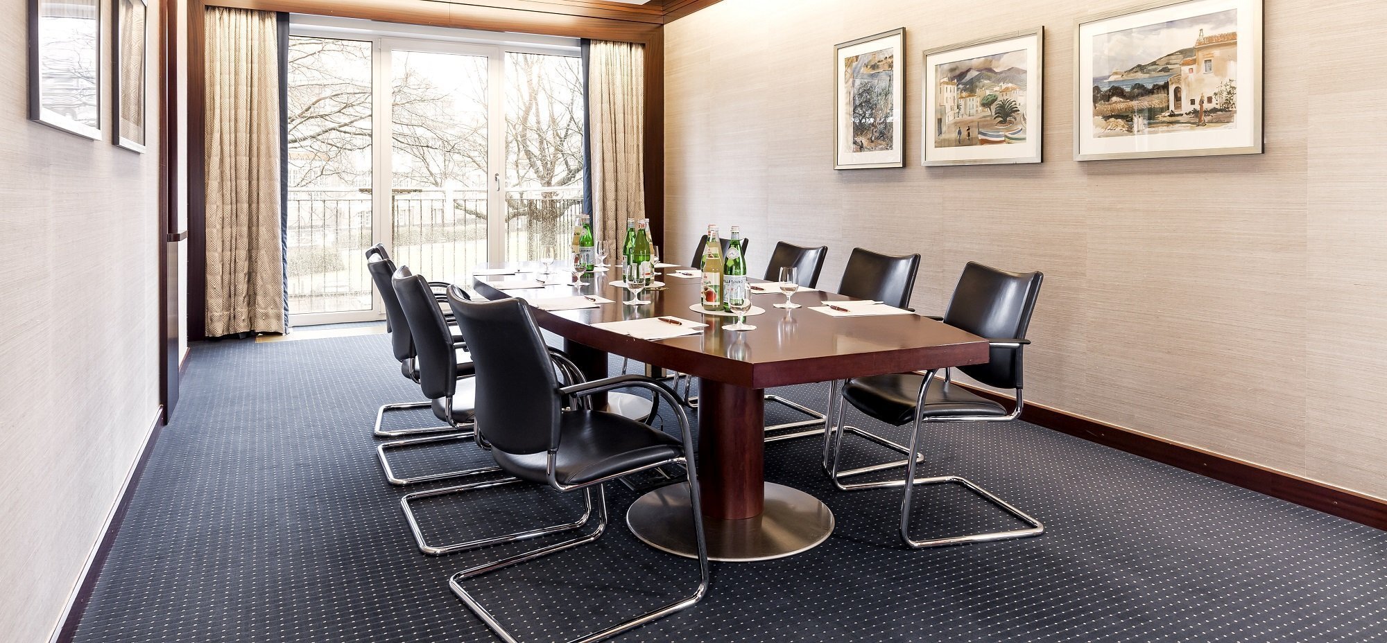 Konferenztisch in Hamburg mit acht Plätzen und Getränken und Gemälden im Hintergrund