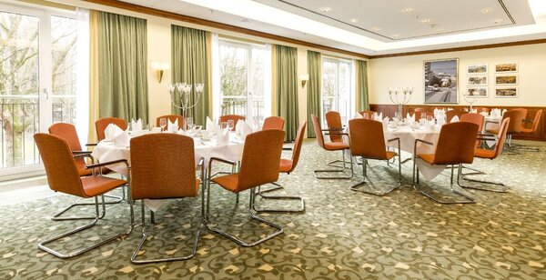 Der Konferenzraum mit runden Tischen und organe-farbenen Stühlen