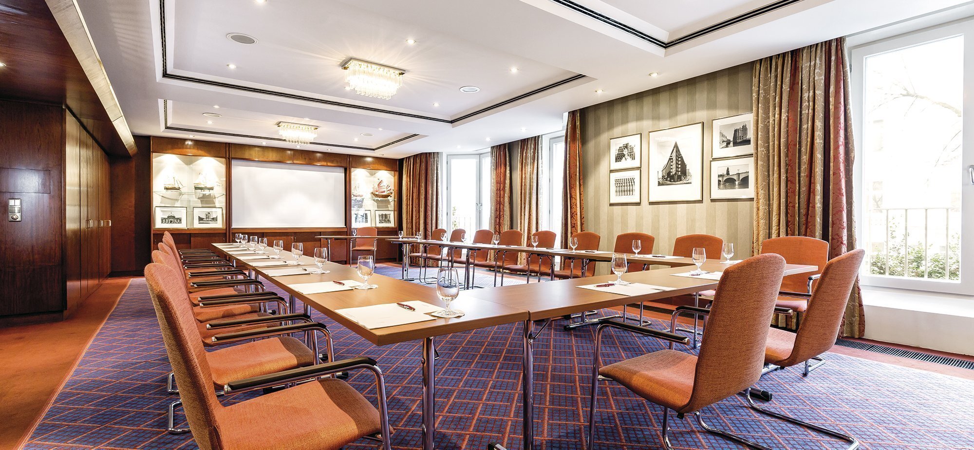 Hufeisenförmiger  Konferenztisch mit blauem Teppichboden und Whiteboard