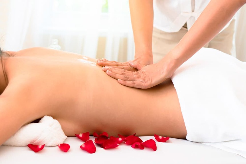 Frau auf dem Rücken liegend mit Rosenblättern bekommt eine Rückenmassage im Hotel Grand Elysée in Hamburg