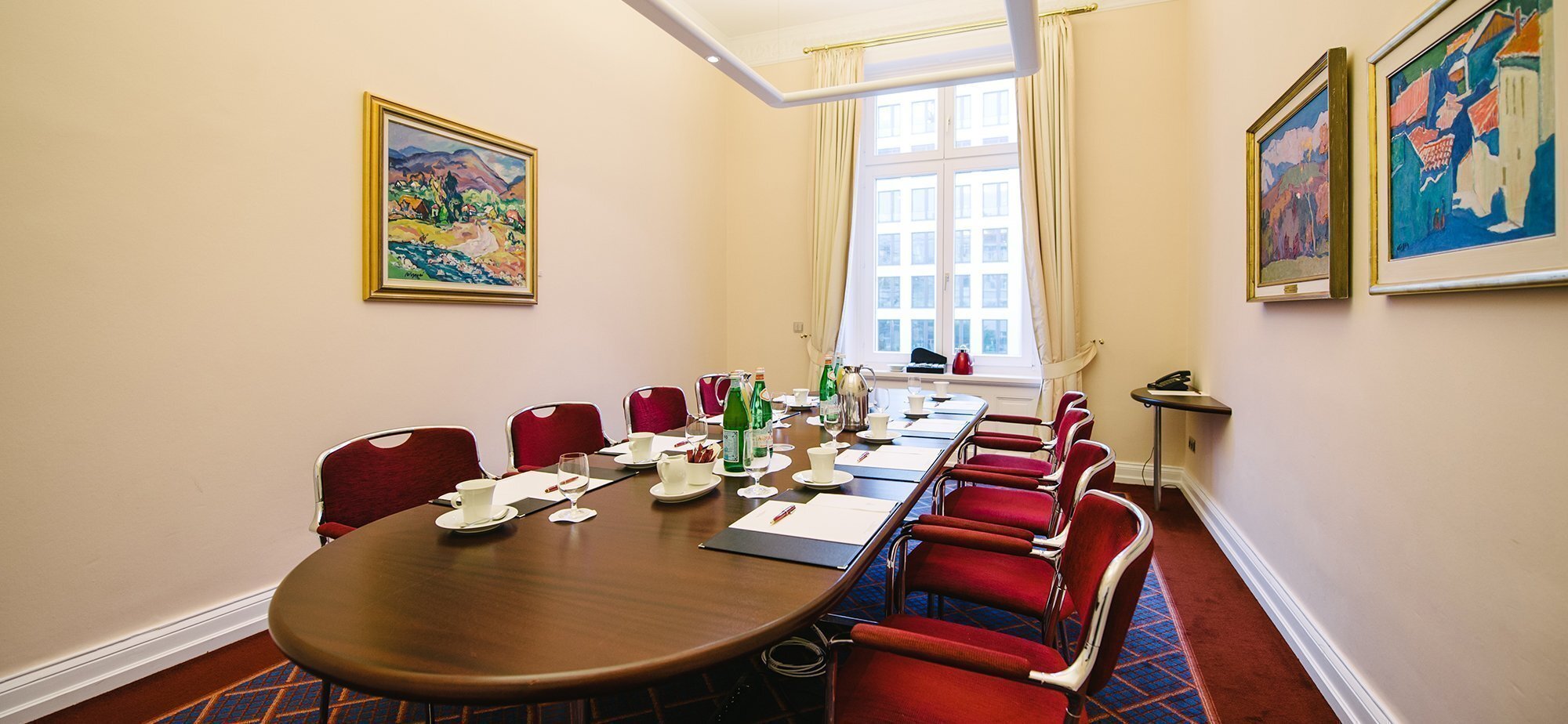 Oval förmiger Konferenztisch mit Getränken und Bildern an der Wand