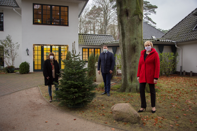 Drei Personen stehen vor einem Haus mit Abstand und Gesichtsmasken
