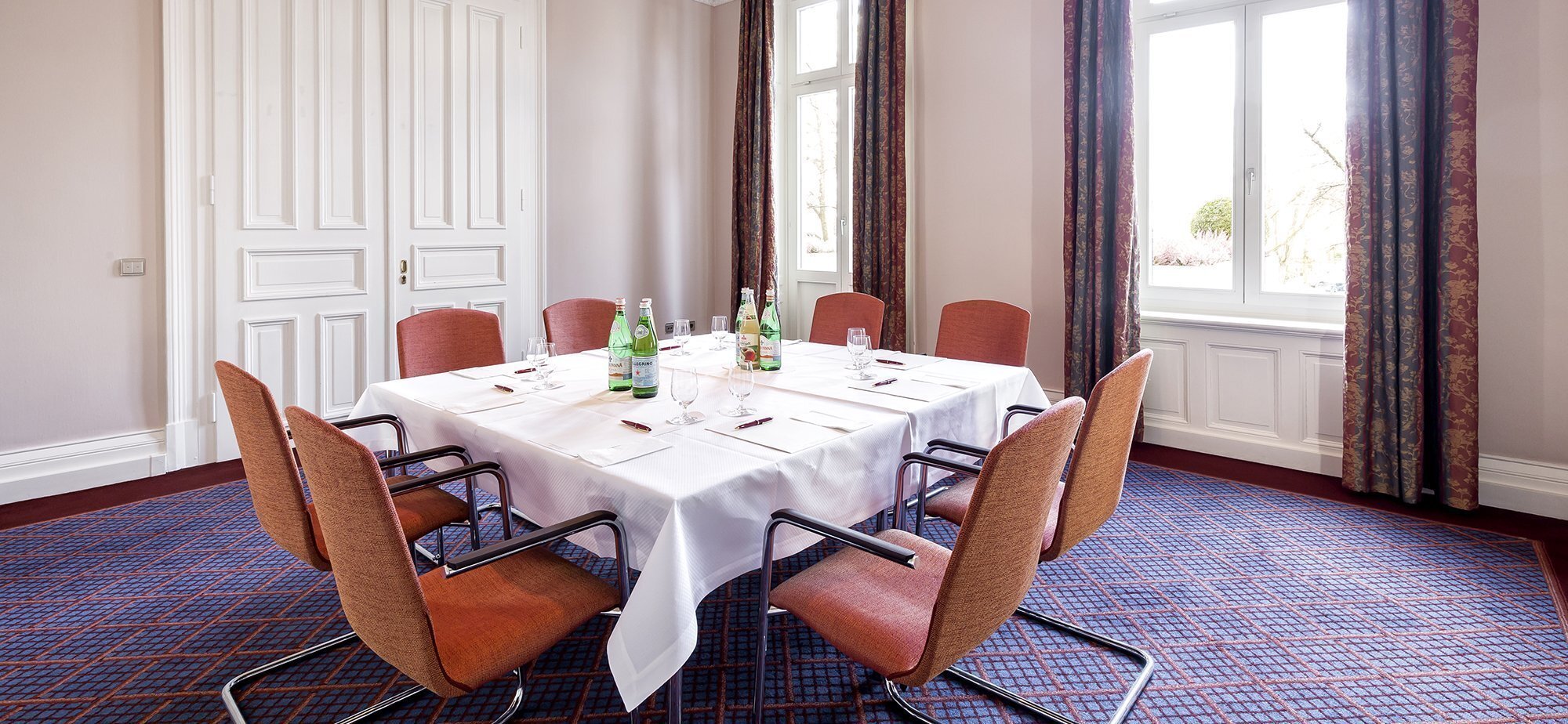 Eckiger Tisch mit Wasserflaschen auf dem Tisch und acht Stühlen